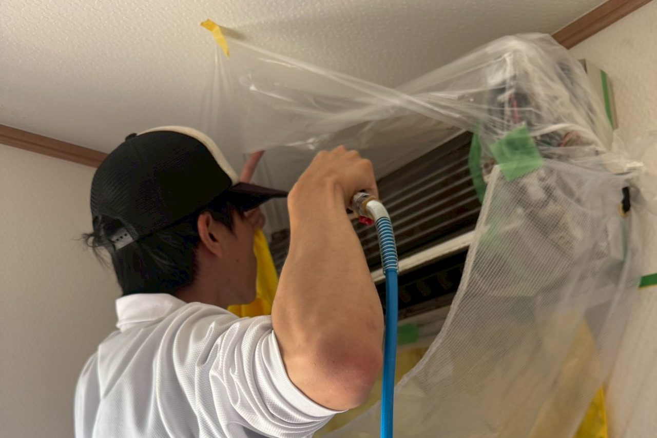 便利屋つくしのスタッフが、養生をしたうえでエアコン内部を高圧洗浄しているところ
